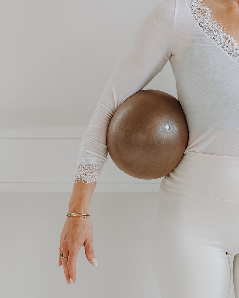 Person in weißen Klamotten mit braunen Ball unter dem Arm.