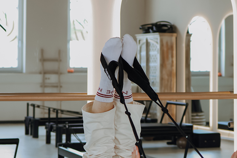 Person zeigt eine Übung im Reformer Pilates Studio.