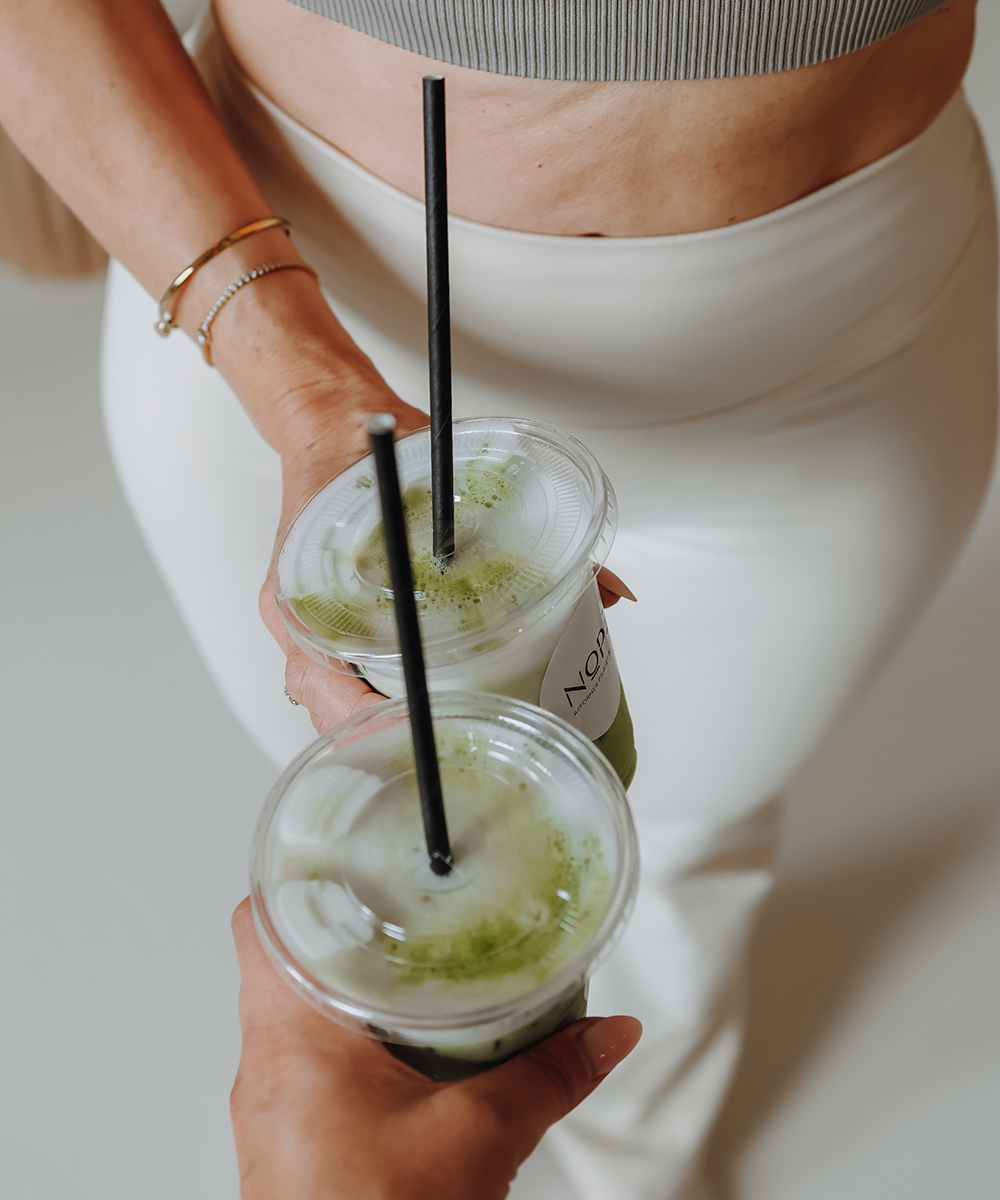 Zwei Personen zeigen ihren Matcha mit dem Unternehmenslogo auf dem Becher.